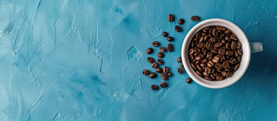 Wall Mural - Bird s eye view of a white cup with coffee beans on a blue concrete backdrop leaving space for text or other elements in the image. with copy space image. Place for adding text or design