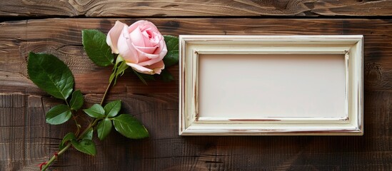Poster - Pink rose beside a blank photo frame on a wooden background including copy space image