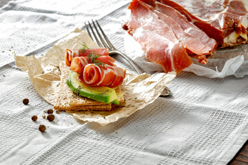 Poster - Sandwiches with crispbread and cold cuts of black forest ham Schwarzwälder Schinken on a kitchen table with gray tablecloth. Copy space for food and drink and products. Delicious nutritious breakfast 