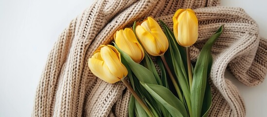 Poster - Top view of a yellow tulip bouquet on a white background next to a knitted sweater with copy space image ideal for celebrating Women s Day and representing spring blooms