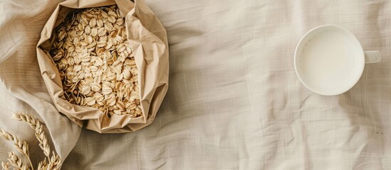 Poster - Natural oat flakes in an eco friendly paper bag on a linen background with copy space image accompanied by a cup of milk