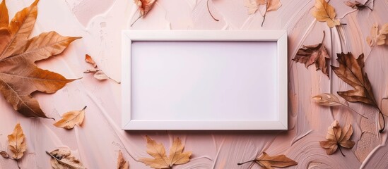 Poster - White photo frame with autumn dried leaves on an autumn background creates a flat lay top view ideal for seasonal promotions with copy space image