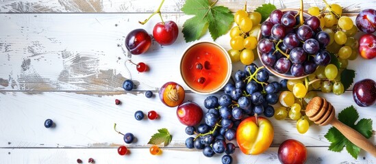 Poster - Top view of fresh grapes blueberries plums and honey on a white tabletop with a wooden background creating a colorful display of seasonal fruits and berries perfect for an organic and healthy eating