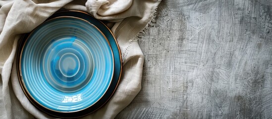 Poster - Bird s eye view of a blue plate on a tablecloth with a napkin offering a blank canvas for your design in the copy space image