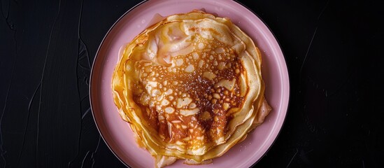 Poster - Top view of a homemade apple Dutch pannekoek pancake served on a pink plate against a black backdrop captured as a flat lay image with copy space available