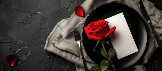 Poster - Top view of an elegant black and white table setting with plates on linen featuring a blank label red rose and silverware creating a visually appealing copy space image