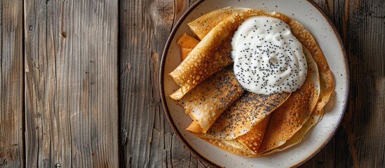 Poster - Delectable poppy seed crepes blinis with creamy sauce on a white plate against a wooden backdrop perfect for a copy space image