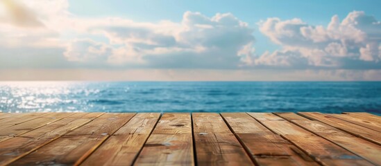 Canvas Print - Outdoor scenery featuring an empty wooden table with a spring sky blue sea and blurred bokeh effect ideal for counter display concepts with copy space image