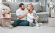 © Maass/peopleimages.com - Couple, love and smile with boxes, clothes and teddy bear for moving, celebration and new home. People, cardboard and happiness for real estate, apartment and property with investment on floor