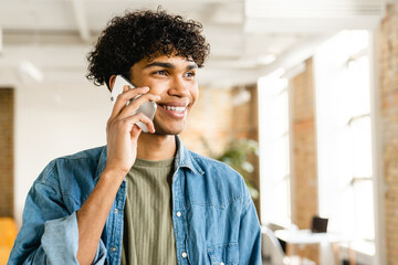 Smart afro mixed-race young business man guy freelancer student manager talking on mobile phone with customers partners colleague while working in the office coworking