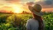 © alexandro900 - Giovane donna che indossa un cappello di paglia che raccoglie verdure fresche in un campo al tramonto, trasmettendo serenità e impegno