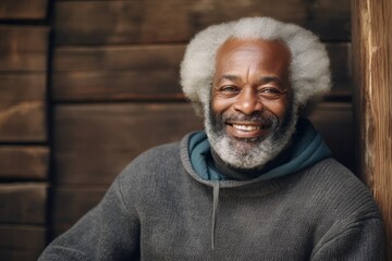 Poster - Portrait of a grinning afro-american man in his 70s dressed in a comfy fleece pullover in front of rustic wooden wall