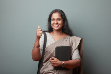 Wall Mural - Smiling Indian woman holding a tablet computer showing thumbs up gesture