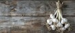 © StockKing - Garlic bulbs with long stalk on wooden table provide a rustic background for a copy space image.