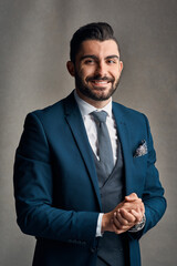 Poster - Happy businessman, portrait and suit with fashion for professional career on a gray studio background. Handsome man or young employee with smile or confidence in formal outfit or ready for business