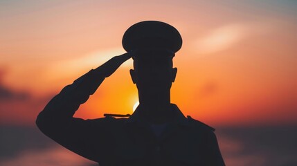 Silhouette of soldier saluting at sunset showcasing honor, patriotism, and dedication with a beautiful serene backdrop of peaceful skies and sea.