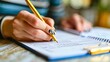 © Roberto - A close-up of a hand writing in a budget planner, with neatly organized columns for expenses and savings, representing careful financial planning.
