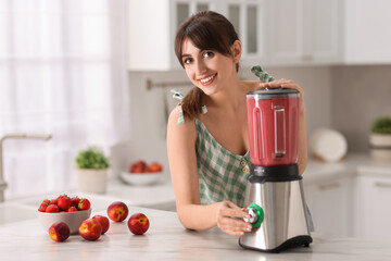 Sticker - Young woman making delicious smoothie with blender at white marble table in kitchen