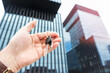 © RomanR - woman holds the keys to a new house or start business in modern glass office center