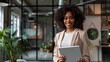 © Marco - brunette woman wearing a suit holding a tablet and smiling at the camera in an office