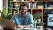 © inthasone - A smiling young man in headphones and glasses sits at a desk working on a laptop and making notes. Happy males in earphones watch webinars or training courses or computers and study online from home.