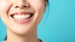 © VarunyuAi - Close-up of a woman's bright smile with white teeth against a vibrant blue background, showcasing dental health and happiness.