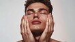 © VarunyuAi - Young man with closed eyes holding his face in a skincare and wellness concept. Smooth complexion and serene expression with soft lighting.