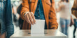 © Andres Mejia - Woman dropping ballot into voting box at polling station