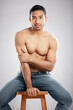 © peopleimages.com - Man, chair and topless with jeans in studio portrait with muscle, strong and pride for healthy body. Person, model or bodybuilder with results, wellness and lose weight for change by white background