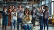 © Business Pics - A group of business people are clapping and celebrating with one woman in a wheelchair. The modern office space shows a diverse group of employees standing around lady in the wheelchair cheering her