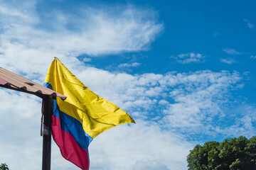 Colombian waving flag in the streets of Colombia, the blue sky in the background