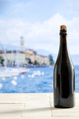 Sticker - Wine glass bottle on white wooden table with copy space for drink and food and products. Blurred seascape and city building background.