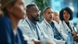 © okfoto - Diverse group of medical professionals listening attentively to speaker at conference, expanding their knowledge and expertise
