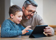 © CineLens2024/peopleimages.com - Tablet, learning and dad with child in home for online classes, school project and lesson. Family, education and father teaching boy on digital tech for help with studying, homework and assignment