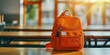 © Daniel - Bright orange backpack on classroom table in morning sunlight backt. 