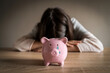 © Zhanna - Sad girl with crying piggy bank on the foreground.