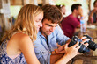 © JordaanExams/peopleimages.com - Show, couple or photographer with camera in photography for travel, comparison or sightseeing. Restaurant, love or tourists sharing photo or picture for memory, honeymoon or holiday trip in Thailand