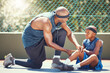 © David/peopleimages.com - Basketball knee injury kid with dad put emergency band aid for sports training game accident at basketball court. African black father and injured child team with healing leg pain and wound plaster