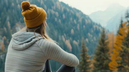 Canvas Print - A woman wearing a yellow hat and a gray jacket is sitting on a bench in a forest