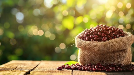 Canvas Print - Red bean in a brown sack on a wooden table outdoors with sunlight and green blur bokeh and lens flare background