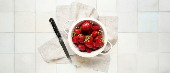 Wall Mural - Colander with fresh sweet strawberries on white tile background