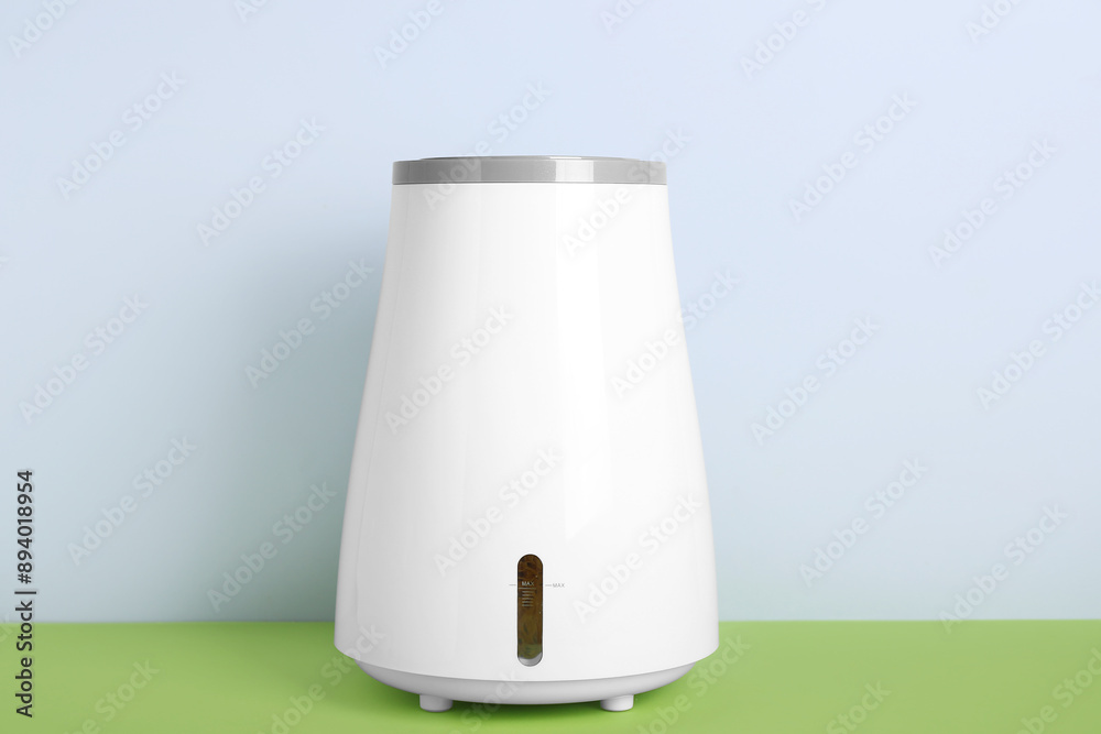 Modern humidifier on table near grey wall