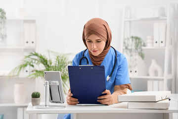 Wall Mural - Female Muslim doctor with clipboard in clinic