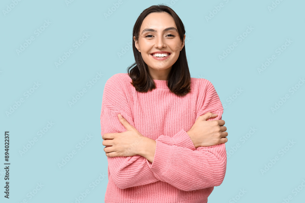 Young woman hugging herself on blue background