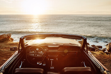 Wall Mural - Convertible, car and sunset at beach for view with road trip, adventure or scenery with mockup space. Empty vehicle, vintage and transport on coast at seaside for ocean sunrise, travel or sightseeing