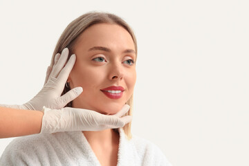 Sticker - Beautician examining face of young woman on white background