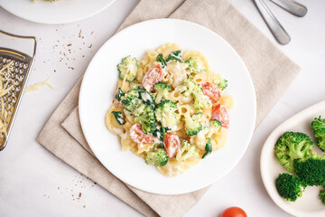 Wall Mural - Plate of tasty pasta with broccoli, tomatoes and napkin on white background