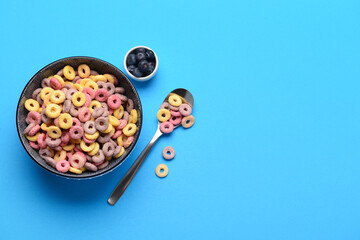 Wall Mural - Bowls with colorful sweet cereal rings and blueberries on blue background