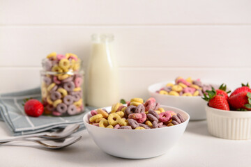 Wall Mural - Bowls with colorful sweet cereal rings, strawberries and bottle of milk on white table