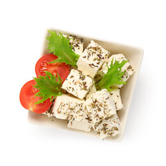 Wall Mural - Bowl with tasty cut feta cheese, spices, salad leaves and tomatoes on white background